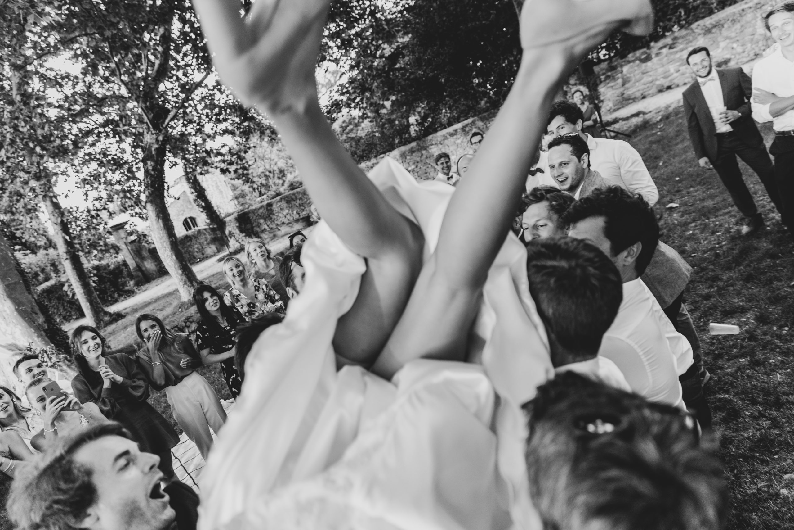 photo mariage noir et blanc la mariée est soulevée par les témoins de son mari